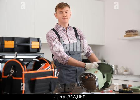 Male technician repairing coffee machine in kitchen Stock Photo