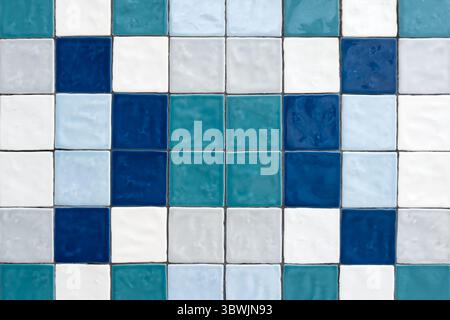A vibrant mosaic of square ceramic tiles in diverse shades of blue, white, and teal, forming an appealing abstract pattern with textured surfaces. Stock Photo