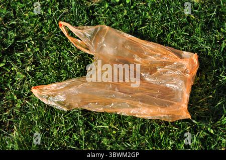 Plastic bag on green grass - trash that pollutes nature Stock Photo