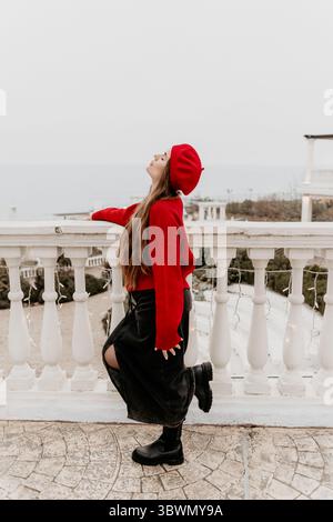 Red beret woman. Stylish woman enjoying a calm moment on an elegant outdoor balcony. Stock Photo