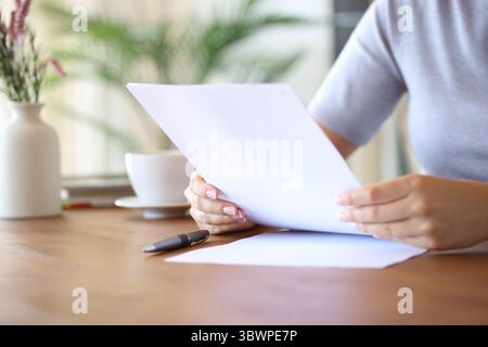 Close up portrait of woman hands reading document on a wooden table at home Stock Photo