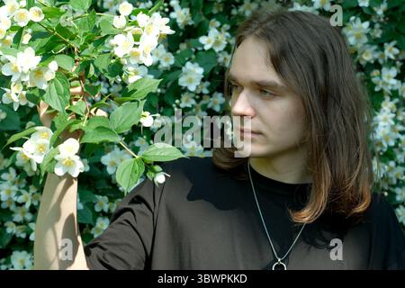 A young man admires flowers in a vibrant garden full of color. Stock Photo