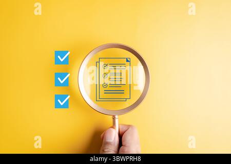 Checklist document review and task verification with magnifying glass focusing on completed items Stock Photo