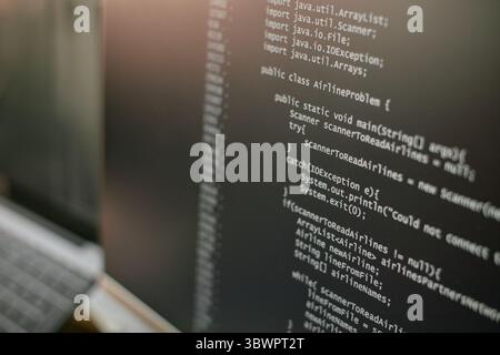 Close up showing computer monitor displaying Java programming code with public class and exception handling visible, focusing on software development and coding process Stock Photo