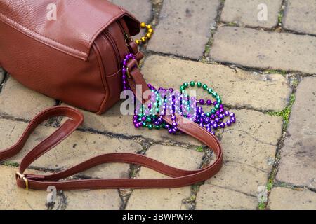 Colourful necklaces draped over the strap of a brown shoulder bag rest on the ground at the Big Rivers music festival in Dordrecht. Stock Photo