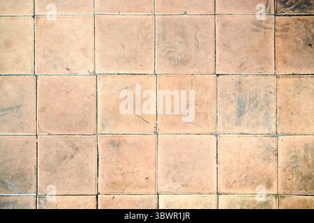 Orange brown white beige old shabby worn out floor tiles with damages cracks dirt caverns potholes and paint stains. Art design background texture Stock Photo