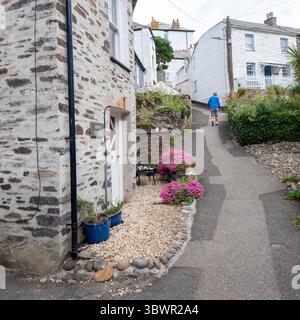 man walks on narrow street near  old white washed houses  in cornish village of port isaac Stock Photo