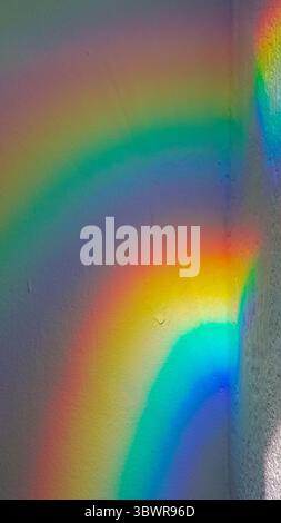 Light creates a rainbow spectrum on a textured wall, showcasing vibrant colors and an abstract pattern Stock Photo