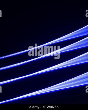 Three parallel blue streaks of light converging on a black background creating a dynamic and energetic composition Stock Photo