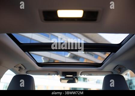 Panoramic sunroof at the car and blue sky. Clean sunroof and view of the sky from the inside or car interior Stock Photo