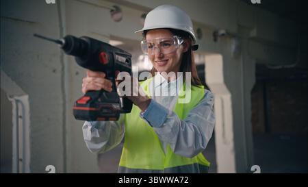 Confident professional Caucasian woman holding electric drill drilling using equipment female girl builder construction building repair engineer Stock Photo