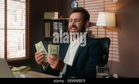 Excited happy Caucasian business man counting money middle-aged professional male businessman count cash dollars finance wealth rich in office at Stock Photo