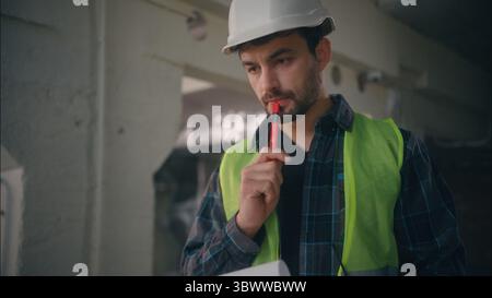 Pensive Caucasian guy builder thinking planning in construction male architect electrician contractor think technician holding notepad man drafting Stock Photo