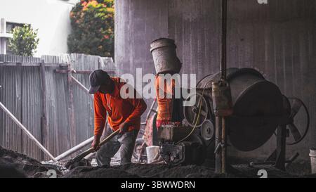 Construction worker mixing building materials like cement, sand, and water to create a strong blend, essential for durable and effective construction Stock Photo