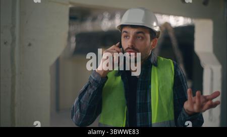 Irritated Caucasian man builder speaking call mobile phone quarrel in construction foreman contractor electrician male communicating smartphone Stock Photo