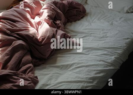 crumpled pink bed sheets on a cozy bed Stock Photo