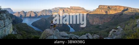Two hikers enjoying the panorama, sunset at Blyde River Canyon with Three Rondawels peak, view of canyon with Blyde River and table mountains in the e Stock Photo