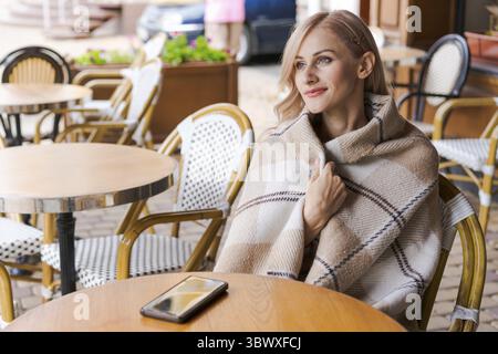 Young woman relaxing in cafe at table on the street, happy caucasian woman Stock Photo