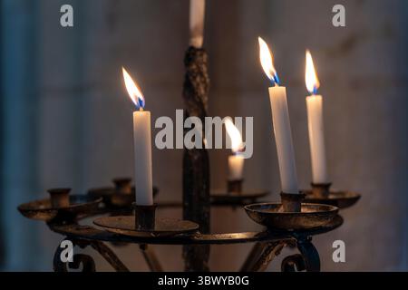 A moody, atmospheric, closeup of wax candles burning in Norwich Cathedral, Norfolk, England. Building started in 1096. Stock Photo