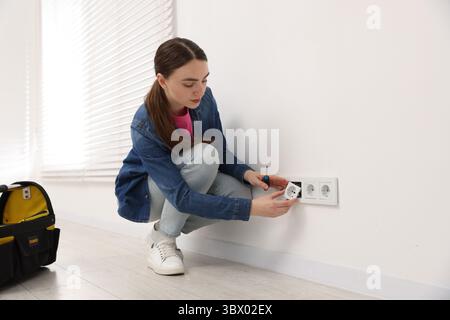 Woman with screwdriver installing new socket at home Stock Photo