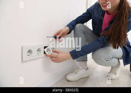 Woman with screwdriver installing new socket at home, closeup Stock Photo