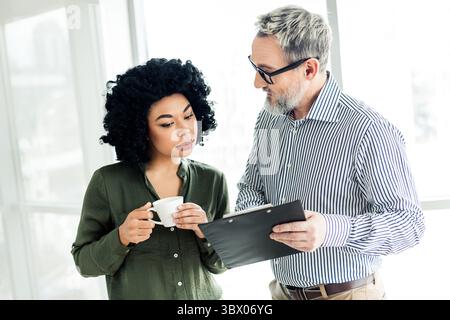 Young professional team members collaborating on a project in a modern office environment with diverse dynamics and ideas Stock Photo