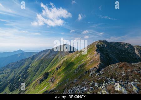 Aerial view of a rugged mountain ridge where shadows dance on the slopes under a blue sky, Jamník, Žilina Region, Slovakia. Stock Photo