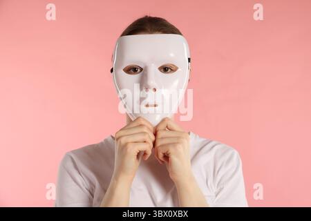 Anonymity. Woman wearing mask on pink background Stock Photo