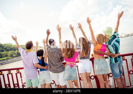 Group of diverse friends enjoying summer vacation on a city bridge waving happily Stock Photo