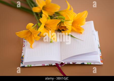 Yellow lilies with notebook for Mother's Day inspiration. Stock Photo