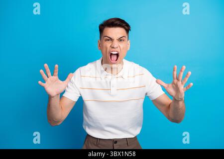 Young man expressing frustration against a blue background showcasing intense emotions with hands raised in a gestural pose Stock Photo