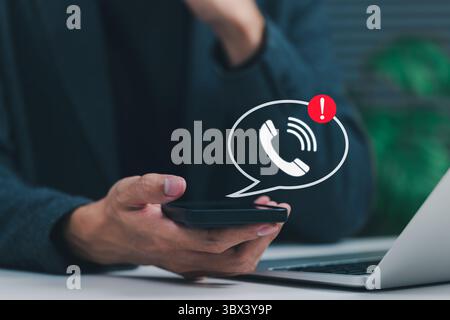Phone Scam Alert and Warning Notification Concept. A person holding smartphone displaying call icon with alert symbol, representing scam call warning Stock Photo