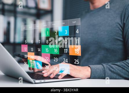 Time management and calendar planning concept. A person using laptop with digital monthly calendar, representing time management, event planning, Stock Photo