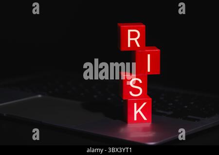 Red Risk Blocks Representing Digital Danger. Stacked red blocks spelling the word RISK placed on laptop, symbolizing digital threats, Stock Photo