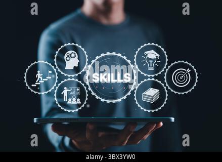 Skills Development and Professional Training Concept. Businessman holds tablet displaying gear icons with word "SKILLS," representing knowledge, Stock Photo