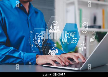Core Values and Corporate Ethics Concept. Businessman using laptop with icons representing core values such as integrity, teamwork, ethics, company Stock Photo