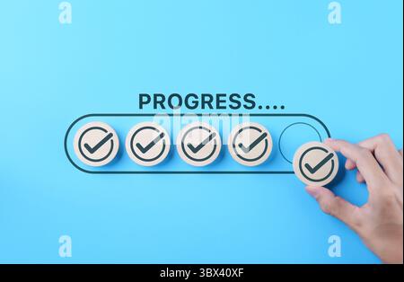 Checklist and task progress tracking concept. A hand placed the final checkmark on round wooden in progress bar, task completion, productivity, goal Stock Photo