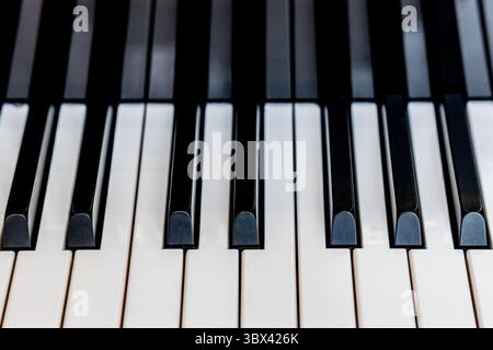 A detailed close-up photograph of black and white piano keys, showcasing the clean symmetry and elegant design of a musical keyboard. This high-resolu Stock Photo