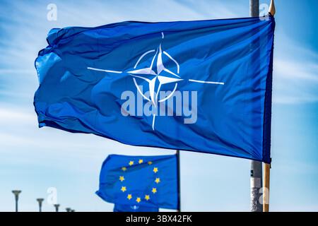 NATO flag waiving on a flagpole with European Union flag behind Stock Photo