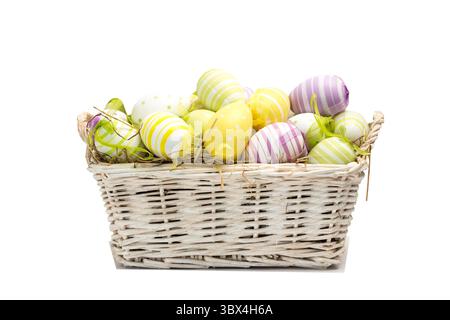 Vector wicker basket sitting on white bg with straw, pastel striped dotted eggs ribbons, copy space. Pastel, rustic, minimalist, seasonal, craft, flor Stock Photo