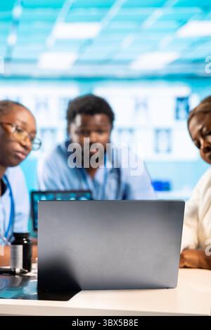 Medical professionals collaborating using diagnostic tools and data to provide expert advice and treatment recommendations. Team of residents in a professional healthcare environment. Stock Photo