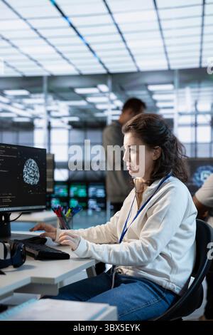 Woman working in high tech AI facility providing computing resources for different workloads. System administrator checking on artificial intelligence data center supercomputers Stock Photo
