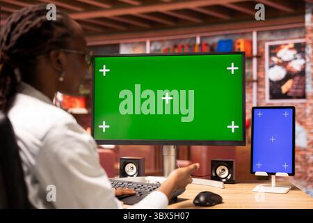 Student at home browsing internet on green screen computer and tablet, doing homework. Girl in apartment reading articles on chroma key PC and mockup device for school tasks Stock Photo