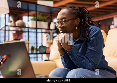 Independent woman using laptop for remote job tasks at home office, doing research and enjoying the benefits of schedule flexibility. Embracing the modern lifestyle of freelance work. Stock Photo