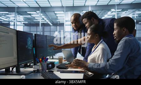 Team of data center technicians maintaining company network infrastructure by configuring and troubleshooting hardware. Teamworking server hub colleagues ensuring optimal system performance, camera A Stock Photo