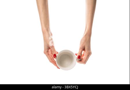 Female hands hold a white ceramic cup on white background. Female hands with fresh red manicure. Isolated on white background. Stock Photo