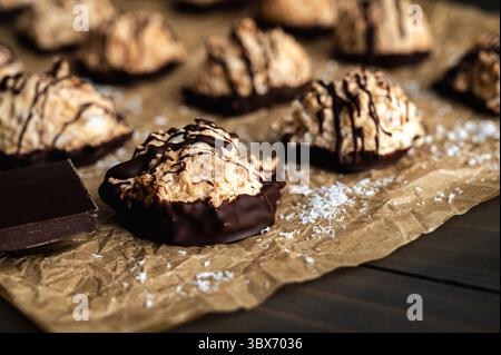 Macaroons Drizzled with Dark Chocolate on Unbleached Parchment Paper: Toasted coconut meringue drop cookies dipped in bittersweet chocolate close-up Stock Photo
