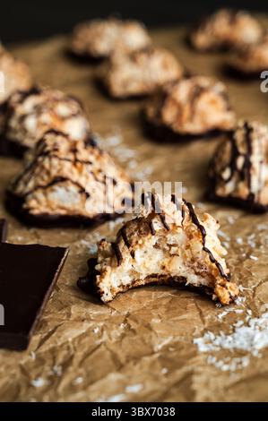 Macaroons Drizzled with Dark Chocolate on Unbleached Parchment Paper: Toasted coconut meringue drop cookies dipped in bittersweet chocolate close-up Stock Photo
