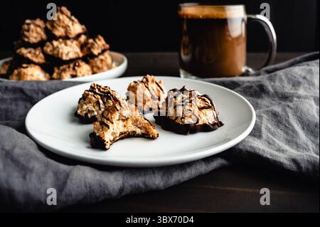 Macaroons Drizzled with Dark Chocolate on a Small Plate: Toasted coconut meringue drop cookies dipped in bittersweet chocolate close-up Stock Photo