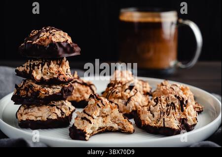 Macaroons Drizzled with Dark Chocolate on a Small Plate: Toasted coconut meringue drop cookies dipped in bittersweet chocolate close-up Stock Photo